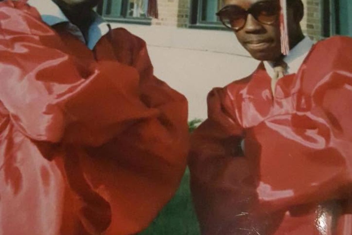 Two Class of 1986 graduates in red caps and gowns on graduation day